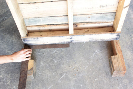 person laying wooden legs next to pallet